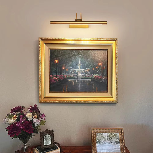 Brass wireless gallery artwork wall light mounted above framed painting on beige wall