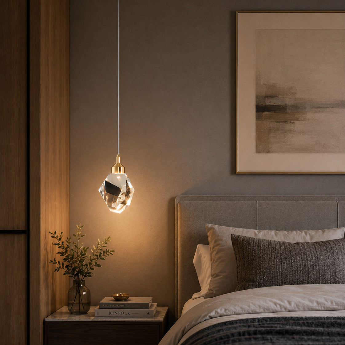 A modern crystal pendant light with a gold canopy hanging over a bed in a styled bedroom setting.