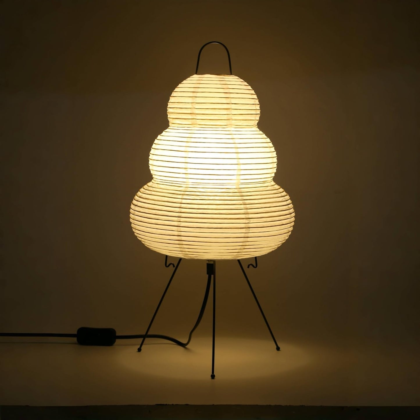 Woven lamp on a stand with a warm glow against a dark background