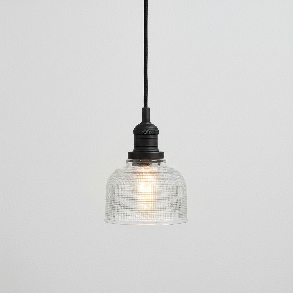 Pendant light with textured glass shade and black metal fixture on a white background