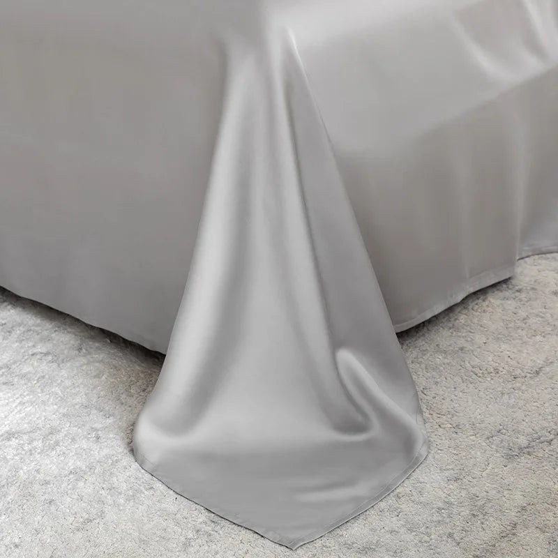 Indulge in luxury with the EleganceSatin Summer Bedding Set, featuring a magnificent bed adorned with a grey sheet and cozy pillows.