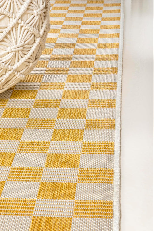 Close-up of a yellow and white checkered rug with a woven basket on top.