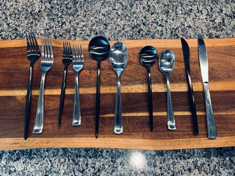 black and chrome steel flatware placed on a wooden piece