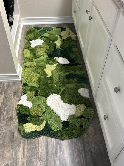 Green camouflage-patterned rug on a wooden floor next to white cabinets.