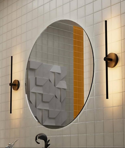 Round mirror with gold frame and wall lights on a tiled bathroom wall