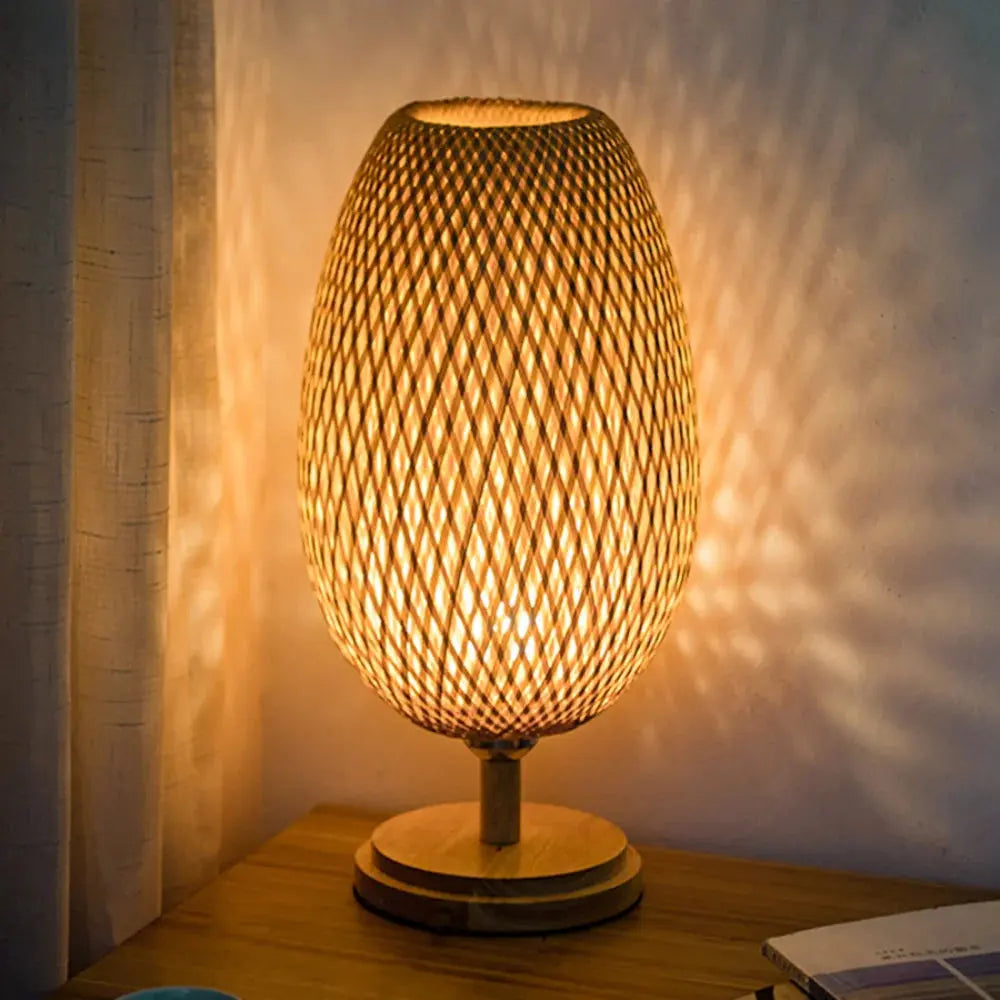 A bamboo essence table lamp with a woven bamboo body and a wooden base, emitting a warm glow.