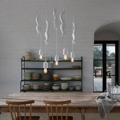 A set of white squirrel-shaped resin pendant lights hanging in a kitchen setting, with a cozy atmosphere highlighted by the light from the pendant lights.