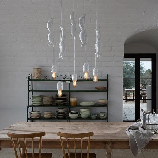 A set of white squirrel-shaped resin pendant lights hanging in a kitchen setting, with a cozy atmosphere highlighted by the light from the pendant lights.