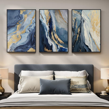 Three abstract paintings above a bed with decorative pillows.