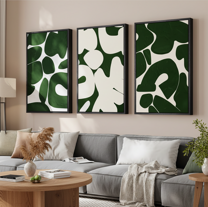 Three framed abstract wall art panels with dark green and white organic shapes, displayed above a gray sofa in a styled living room.