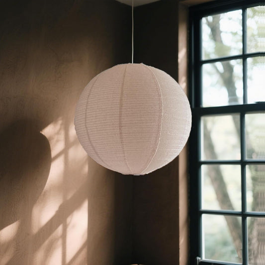 Beige spherical lampshade hanging in a room with a window in the background