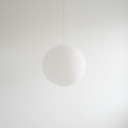 A white spherical paper lantern-style pendant light hanging from a thin cord against a plain white wall.