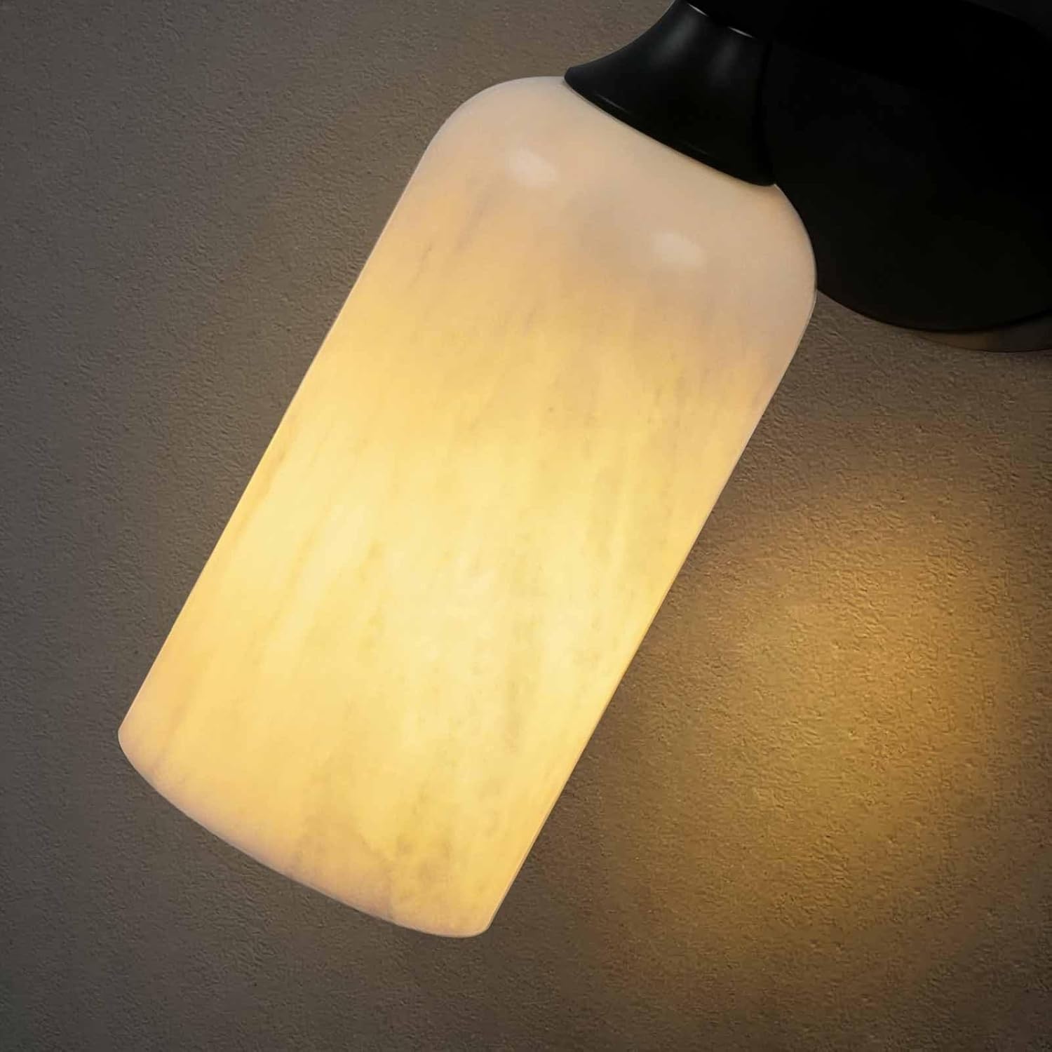 Wall-mounted light fixture with a textured beige lampshade on a dark wall.