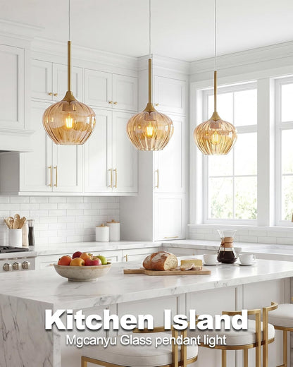 Modern kitchen with marble island, glass pendant lights, and white cabinets.