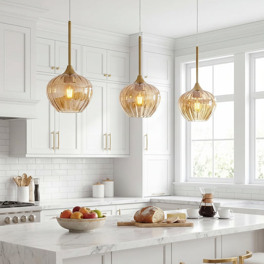 Modern kitchen with marble island, glass pendant lights, and white cabinets.