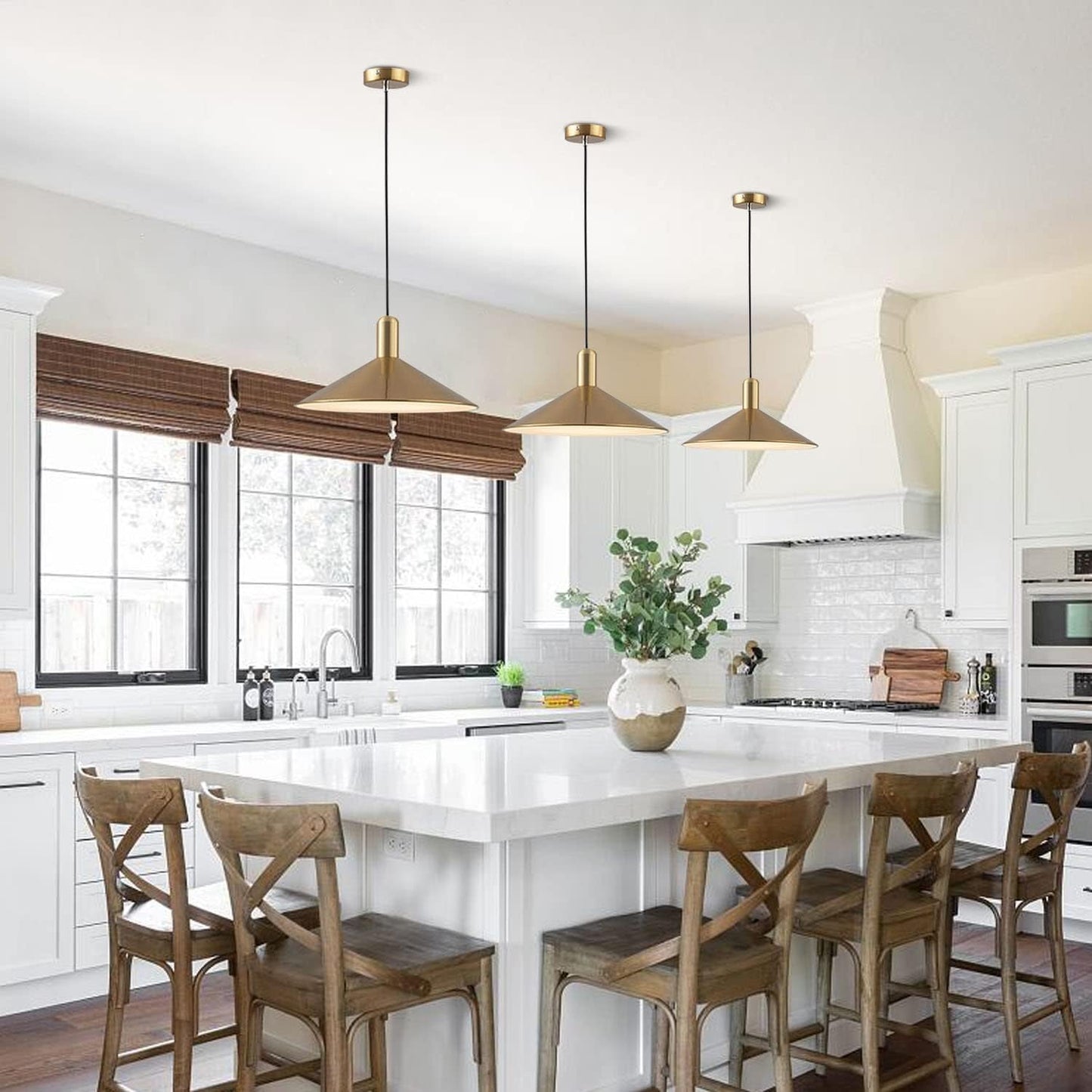 Modern kitchen with white countertops, wooden chairs, and pendant lights.