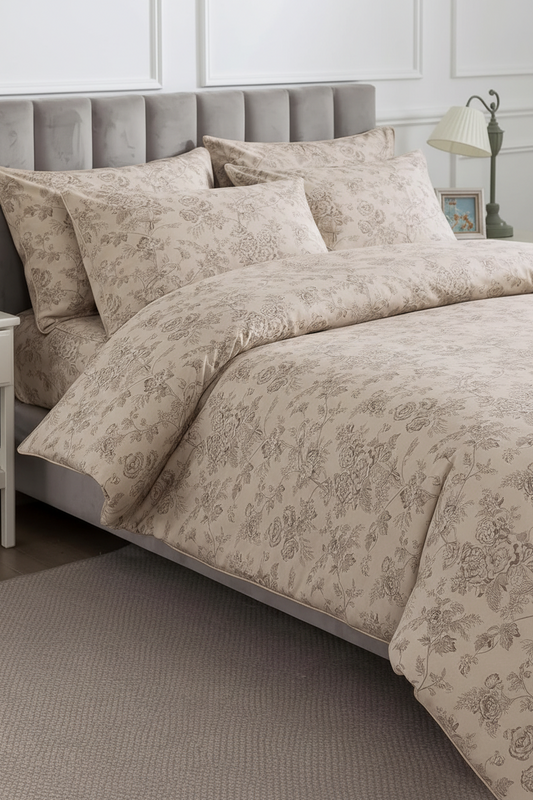 A beige and taupe floral-patterned duvet cover and pillowcase set styled on a bed with a gray tufted headboard in a bedroom setting.