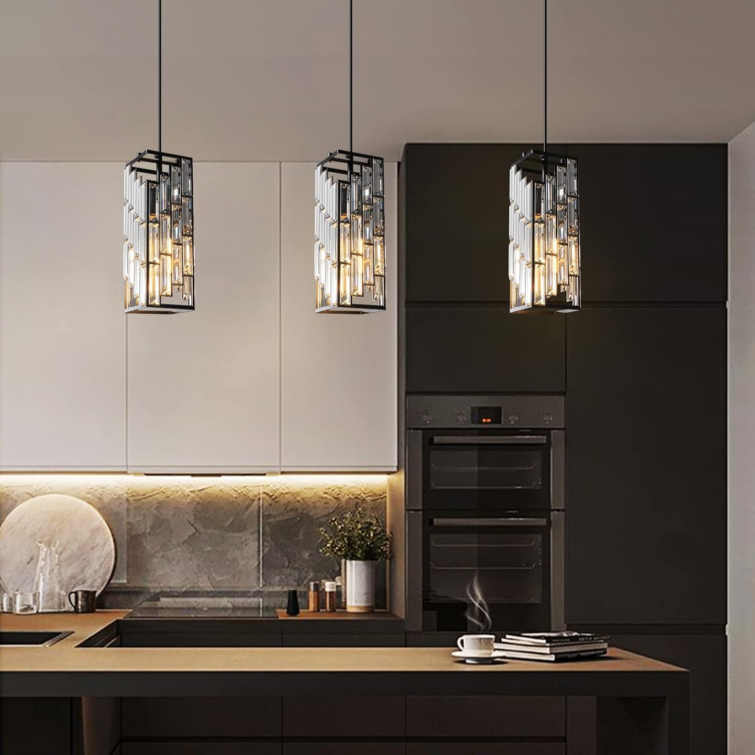 Modern kitchen with black and white cabinetry, pendant lights, and a stove.
