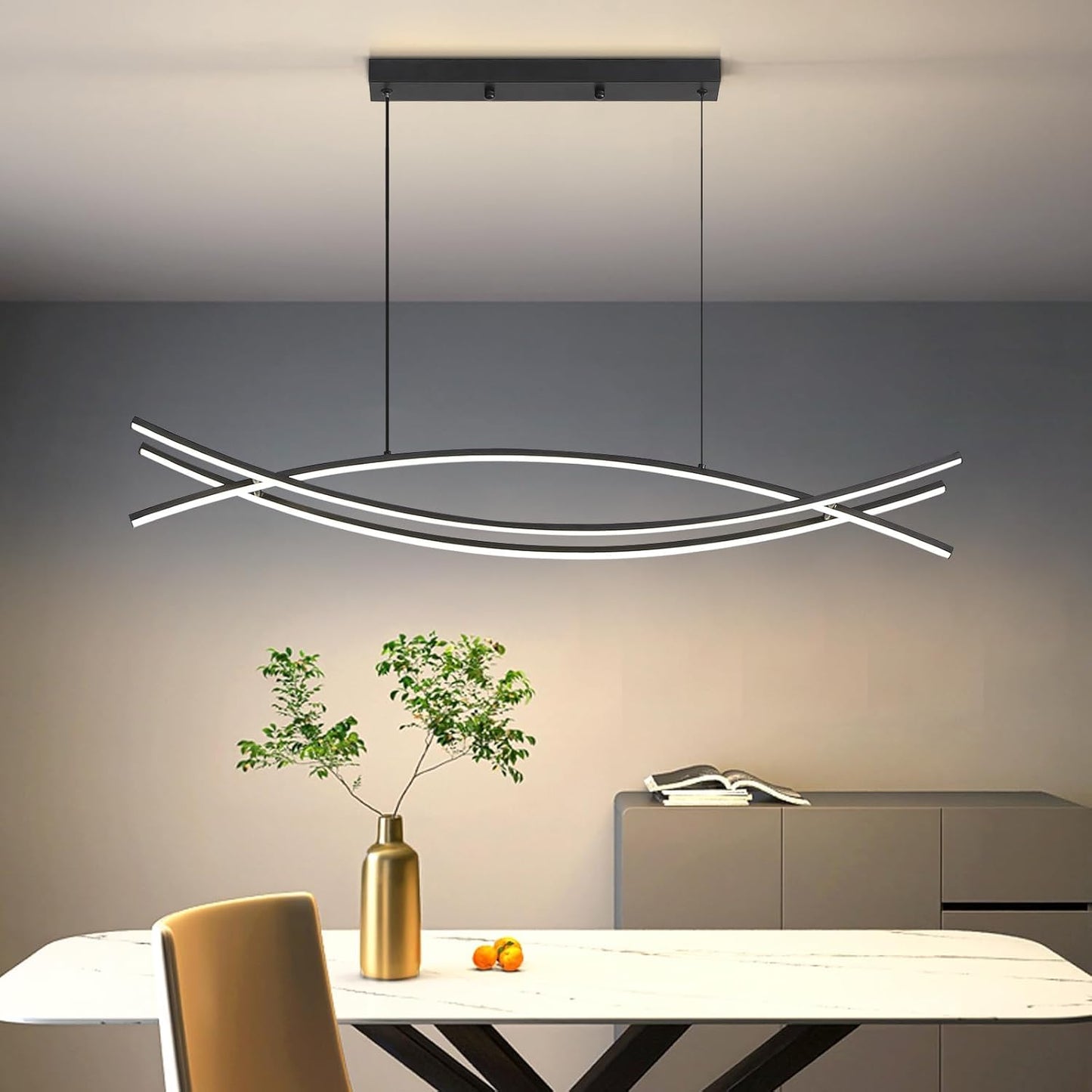 Modern pendant light fixture in a room with a table and decorative items.
