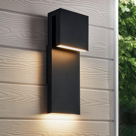 Modern outdoor wall light fixture on a textured wall with greenery in the background