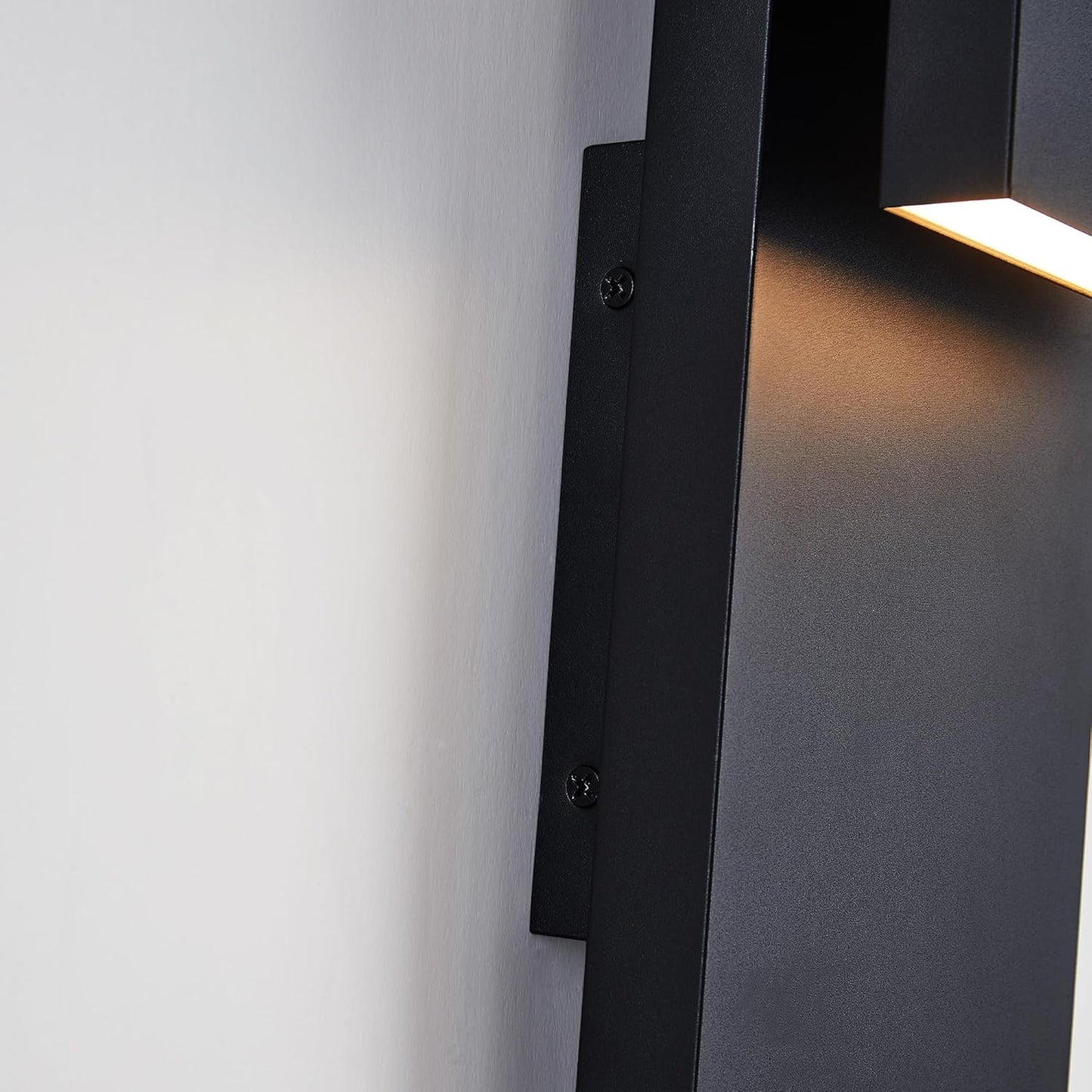 Modern black wall-mounted light fixture on a white wall