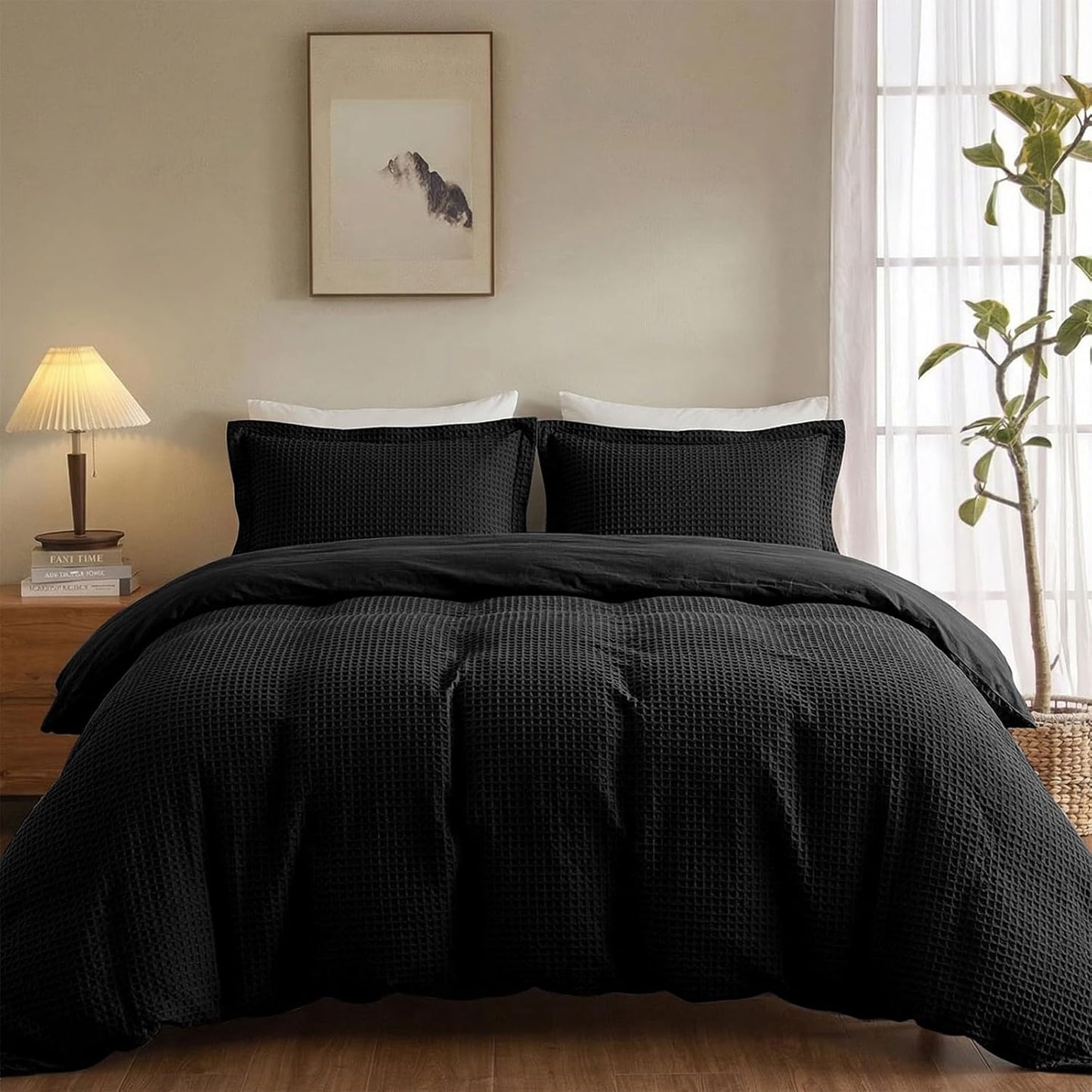 A black textured waffle-weave bedding set, including a duvet cover and two matching pillowcases, styled on a bed in a warm, modern bedroom setting.