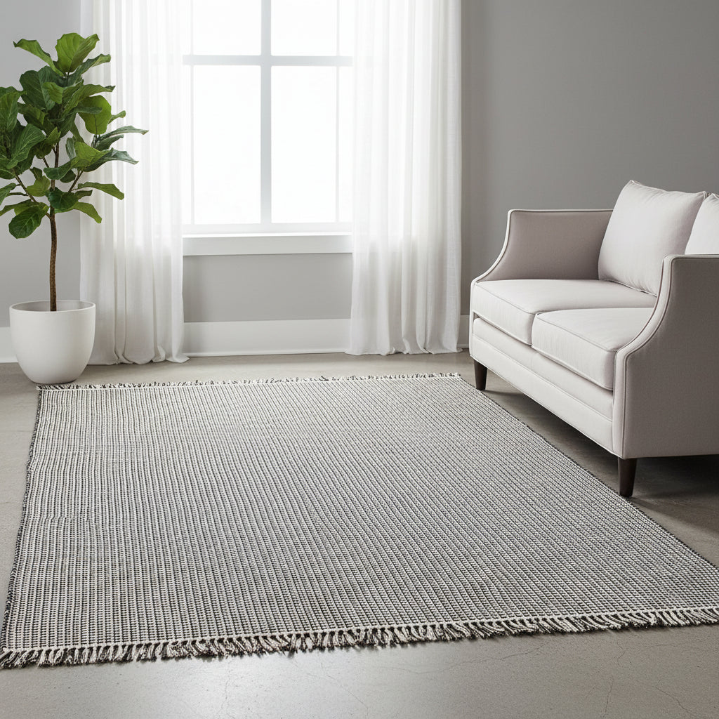 Living room with a gray woven rug, white chair, and yellow blanket.
