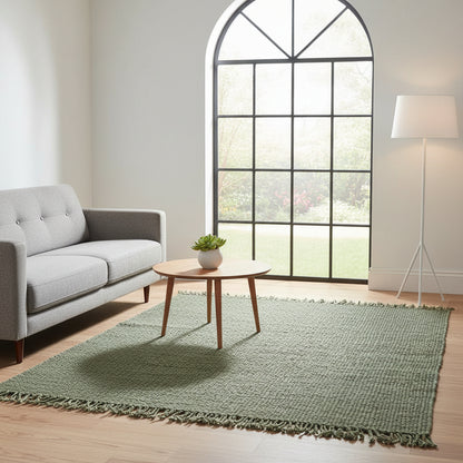 Living room with a green rug, gray sofa, and round wooden table.