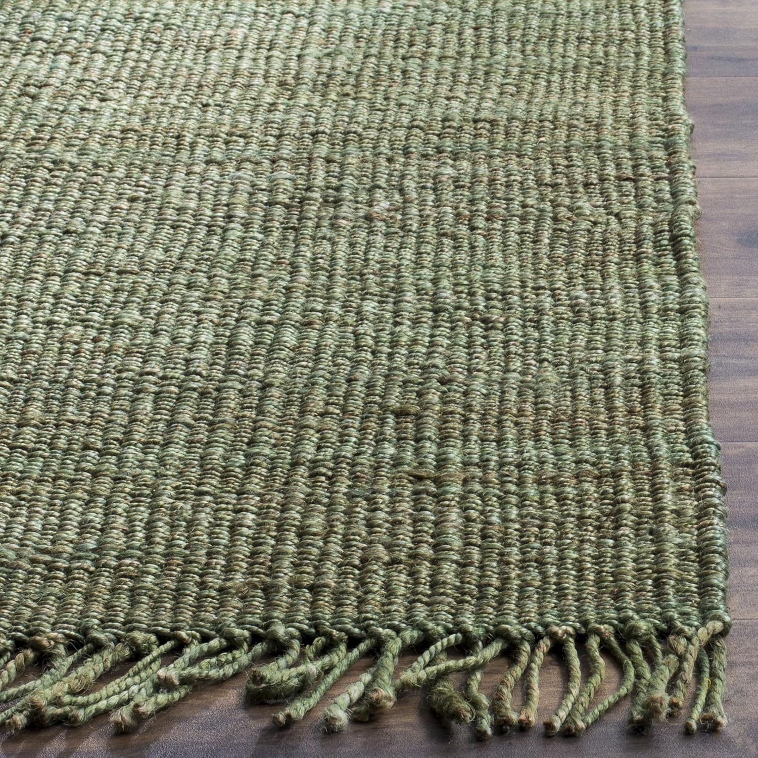 Green textured rug with tassels on a wooden floor