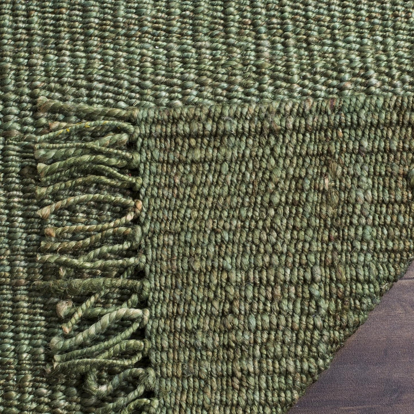 Close-up of a green textured rug with a fringed edge.