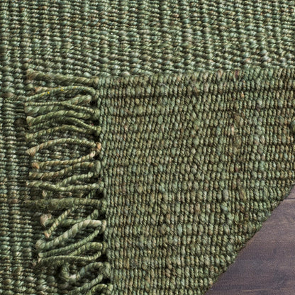 Close-up of a green textured rug with a fringed edge.