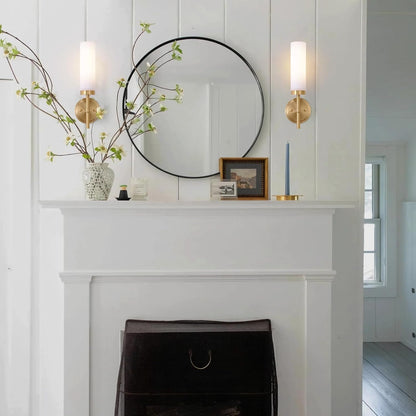 Decorative mantel with a mirror, candles, and a vase on a white wall.