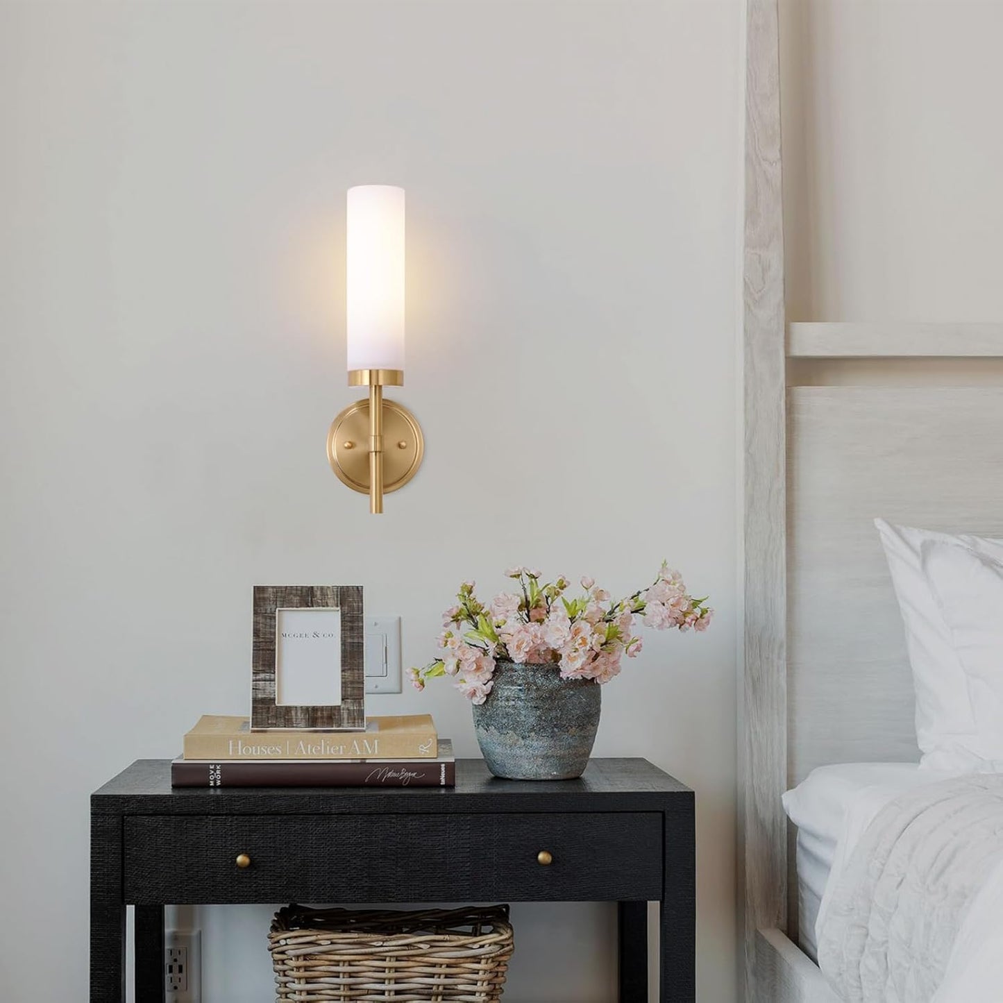 Decorative nightstand with lamp, books, and flowers next to a bed.