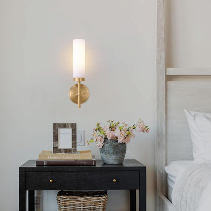 Decorative nightstand with lamp, books, and flowers next to a bed.