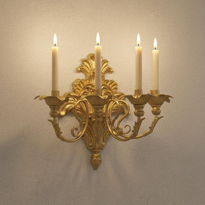 Gold wall sconce with four lit candles on a beige wall.