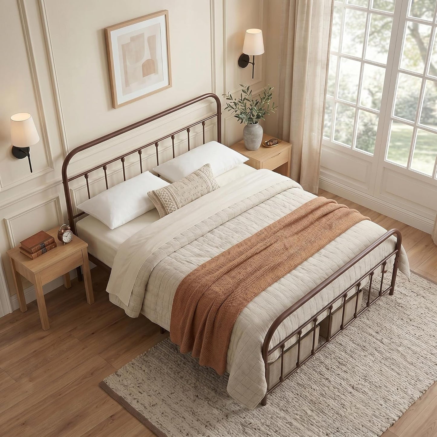 A bed with a dark brown metal frame, dressed in cream bedding and a rust-colored throw blanket, styled in a warm, modern bedroom setting.