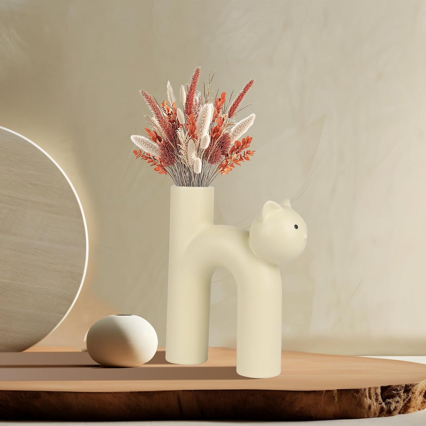 Cat-shaped vase with dried flowers on a wooden shelf against a beige wall