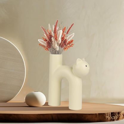 Cat-shaped vase with dried flowers on a wooden shelf against a beige wall