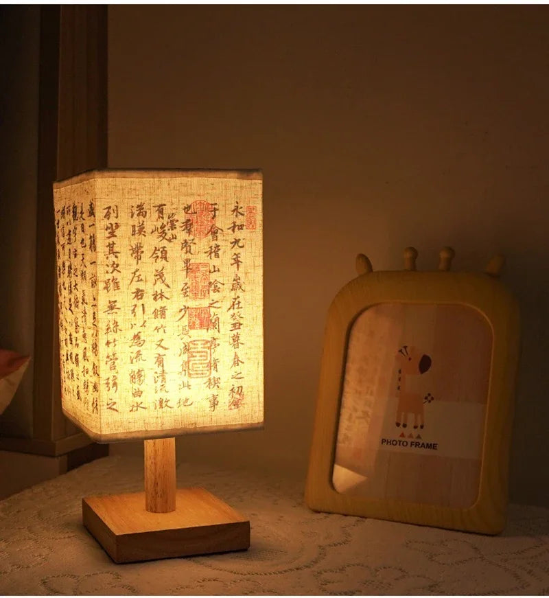 Table lamp with illuminated fabric shade featuring Chinese characters, next to a photo frame with a giraffe illustration.