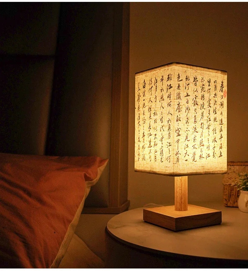 Table lamp with illuminated paper shade featuring text on a bedside table.