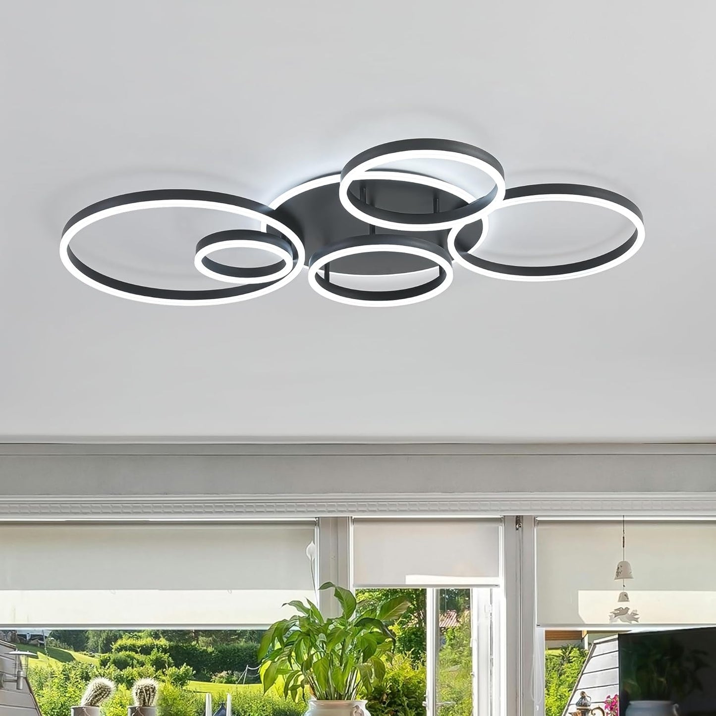 Modern ceiling light fixture in a room with large windows and plants