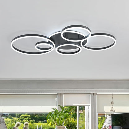 Modern ceiling light fixture in a room with large windows and plants