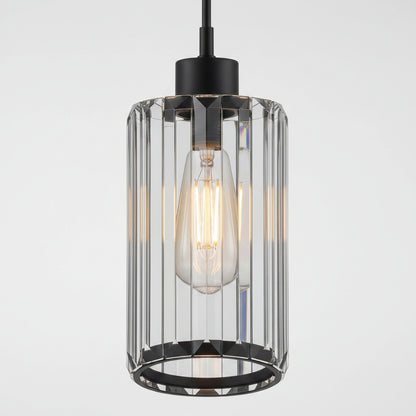 A modern industrial pendant light with a black metal canopy and base, featuring a clear glass cylindrical cage with vertical fluted bars and a glowing warm Edison bulb inside.