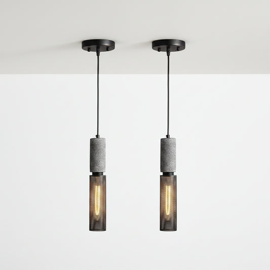 Two matching pendant lights shown side by side on a plain white background. Each light has a black ceiling canopy and cord, a textured gray cylindrical middle section, and a dark mesh lower shade with a glowing warm bulb inside.