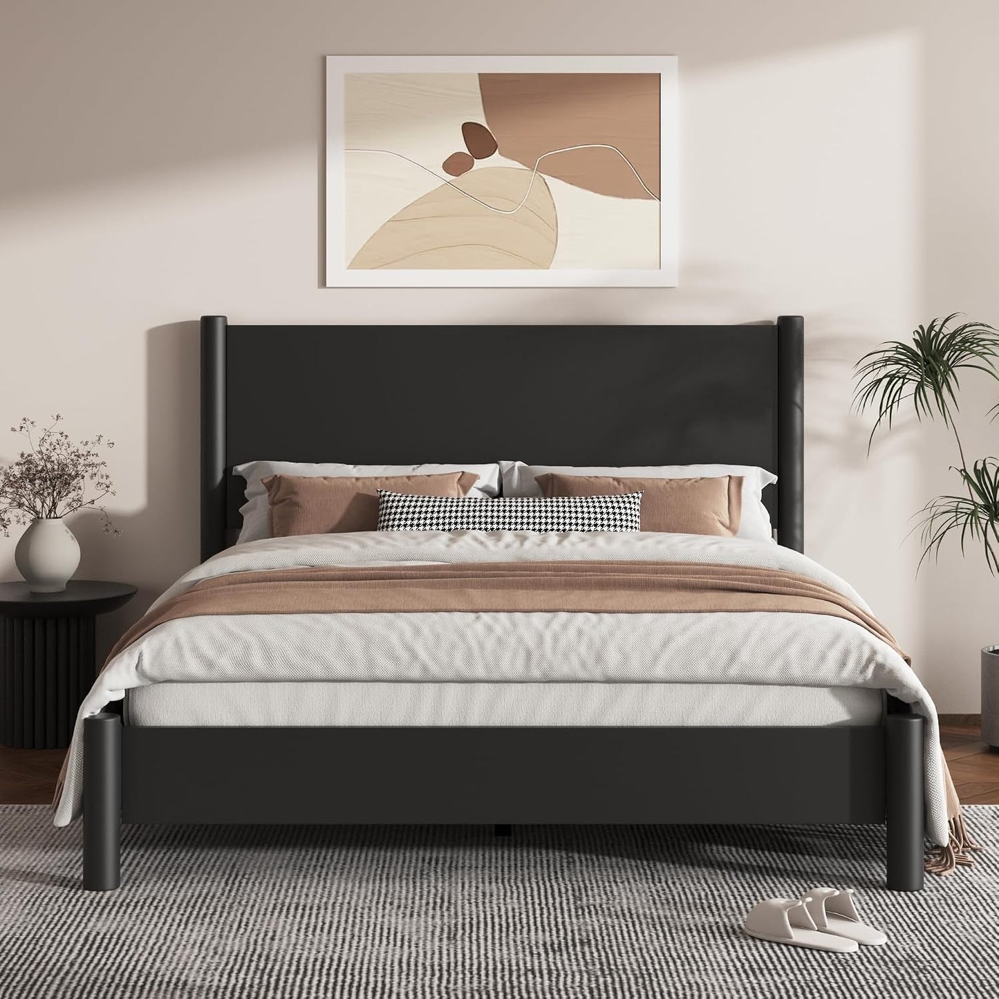 A modern black wooden bed frame with a tall upholstered headboard, styled with white and beige bedding, set in a minimalist bedroom with a gray rug, side table, and abstract wall art.
