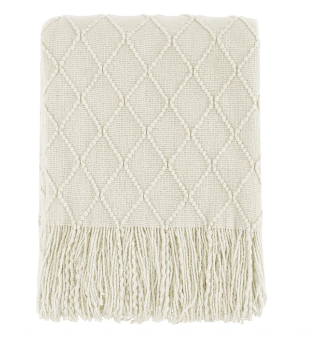 White knitted throw blanket with diamond pattern and tassels on a white background