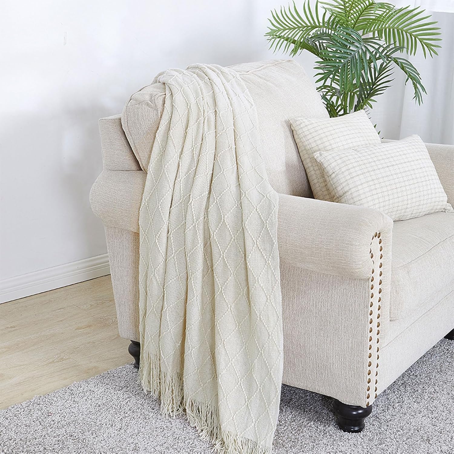 Beige blanket draped over a beige armchair with a plant in the background