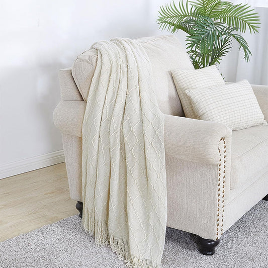 Beige blanket draped over a beige armchair with a plant in the background