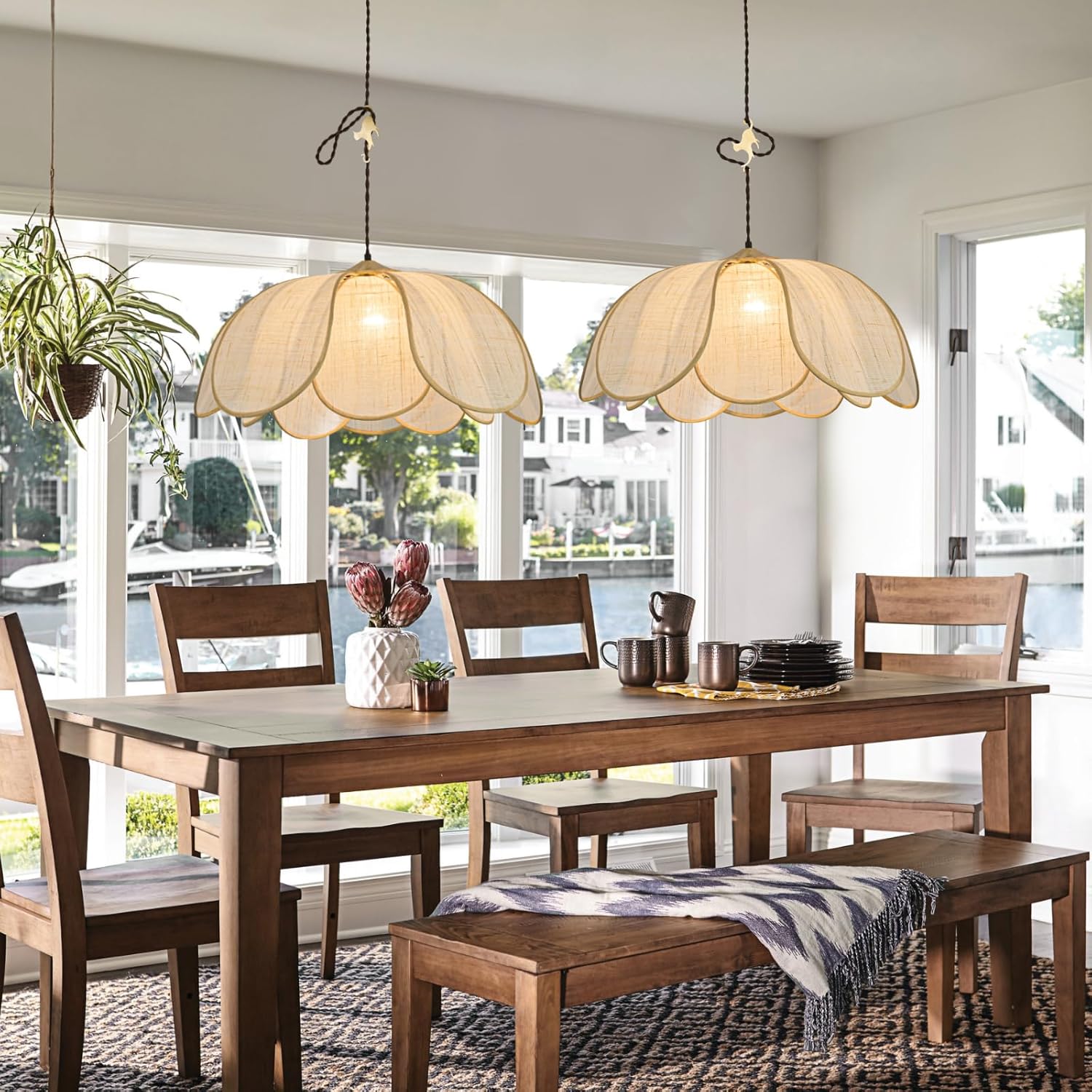 Dining room with wooden table, chairs, and pendant lights in a bright room.