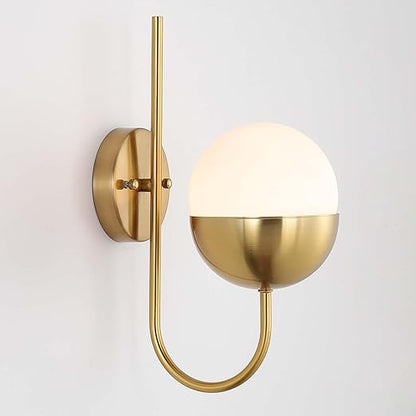 Gold wall sconce with a white globe shade on a light gray background